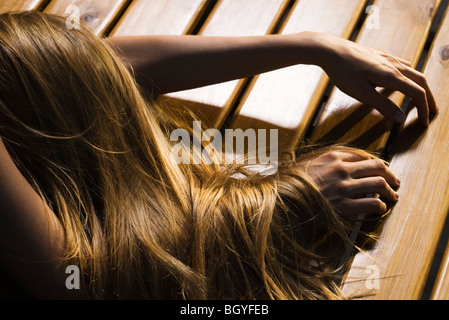 Donna disteso a faccia in giù sul pavimento, capelli lunghi che coprono il braccio, ritagliato Foto Stock