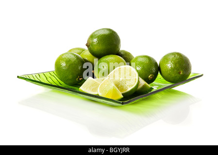 Limette fresche sulla lastra di vetro verde isolato su sfondo bianco Foto Stock