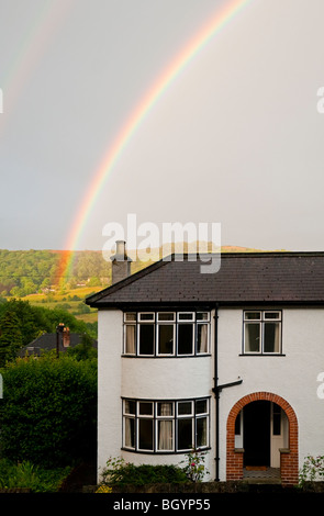 Rainbow oltre ad arco casa suburbana con colline in lontananza Foto Stock