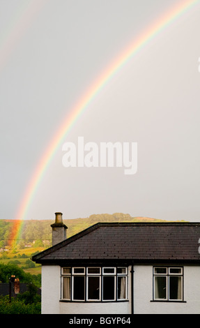 Rainbow oltre ad arco casa suburbana con colline in lontananza Foto Stock