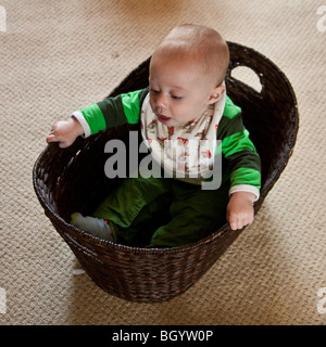 Baby boy (otto mesi) giocando in un cestello Foto Stock