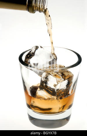 Whiskey versata sulle rocce in un bicchiere old fashioned su sfondo bianco Foto Stock