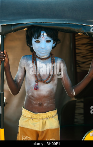 Ragazzo indiano, faccia dipinta come il dio indù Shiva in piedi in un rickshaw. Andhra Pradesh, India Foto Stock