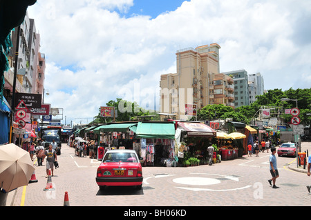 Aria aperta negozi, cartelli pubblicitari, gli acquirenti, i taxi e i furgoni in corrispondenza di un nodo stradale presso il Mercato Stanley, Hong Kong, Cina Foto Stock