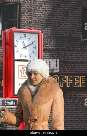 Ragazza giovane alla street clock sull'angolo di Danziger e Lange Reih strade. Amburgo, Germania Foto Stock