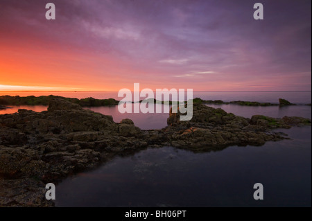 Bel tramonto sull'oceano con coste rocciose Foto Stock