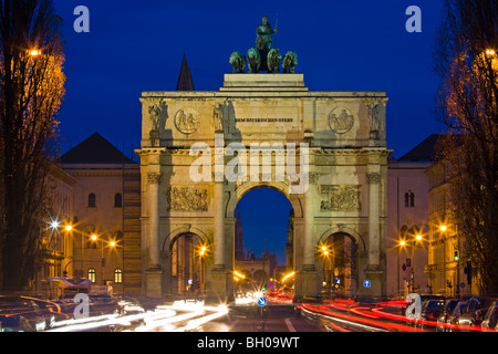 Il Siegestor (Vittoria Gate) con il traffico che fluisce intorno al tramonto nel quartiere di Schwabing nella città di München (Monaco di Baviera), B Foto Stock
