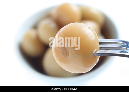 Una cipolla sott'aceto su una forcella con una ciotola di loro in background. Foto Stock