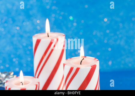 Tre strisce rosso bianco Natale candele su una glitter sfondo blu Foto Stock