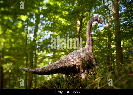 Toy brachiosaurus davanti di alberi decidui Foto Stock