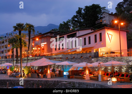 Bar sotto ombrelloni sul lungomare illuminato promenade di Ascona, Ascona, Lago Maggiore, Lago Maggiore, Ticino, Svizzera Foto Stock