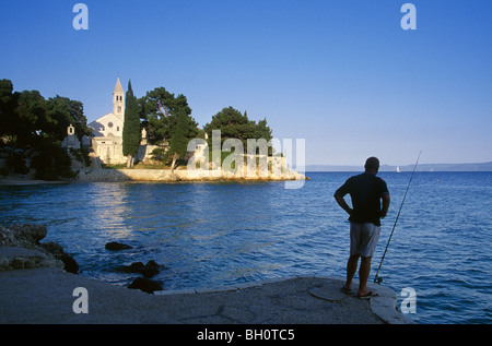 Pescatore sulla spiaggia di fronte all'abbazia domenicana sotto il cielo blu, isola di Brac, Mare Adriatico croato, Dalmazia, Croazia, Europa Foto Stock