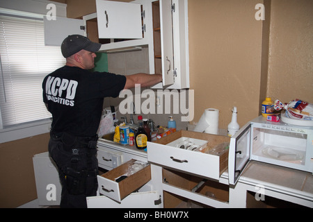 Funzionari di polizia da strada Unità narcotici tactical squad ricerca di droga, armi, denaro etc in sospetti residence. Foto Stock