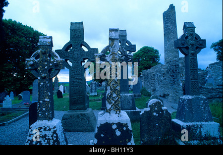 Alta incrocia davanti alle rovine della abbazia di Monasterboice al tramonto, nella contea di Louth, Irlanda, Europa Foto Stock