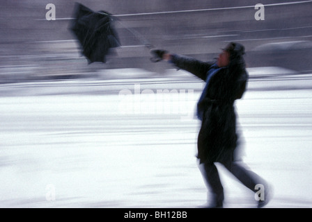Uomo d'affari in tempesta di neve con la brolla soffiata dal vento, New York City, USA anni '1990 retrò Foto Stock