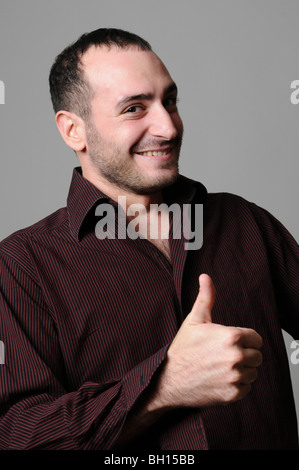 Ritratto di un giovane sorridente modello maschile nel suo 20s dando il pollice in alto modello di rilascio disponibili Foto Stock