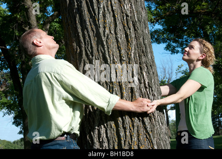 Paio di tenere le mani attorno al grande albero, Assiniboine Park, Winnipeg, Manitoba, Canada Foto Stock