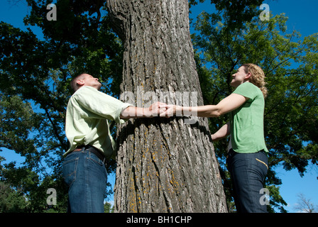 Paio di tenere le mani attorno al grande albero, Assiniboine Park, Winnipeg, Manitoba, Canada Foto Stock