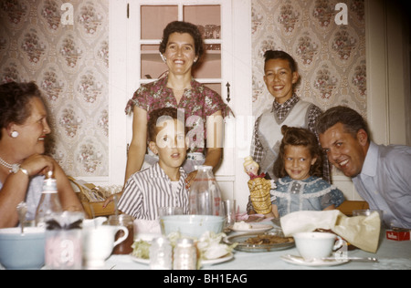 La famiglia a tavola per cena durante gli anni cinquanta. carta da parati vintage poste orizzontale ritratto moda 50s pasto pranzo insieme sorriso Foto Stock