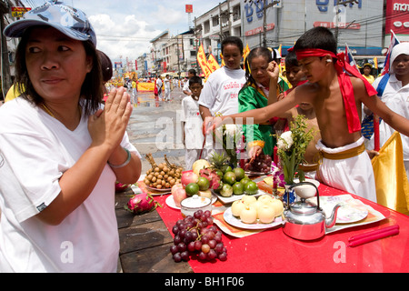 Giovani uomini benedire lato strada offerte durante il Festival vegetariano, celebrato a Krabi, Thailandia Foto Stock