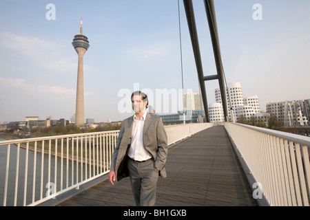 Uomo che cammina sulla passerella Media Harbour, Duesseldorf, capitale dello stato di NRW, Renania del nord-Westfalia, Germania Foto Stock