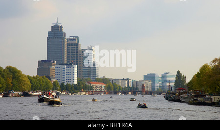 Guida di barche sul fiume Amstel, edifici alti in background, Amsterdam, Paesi Bassi, Europa Foto Stock