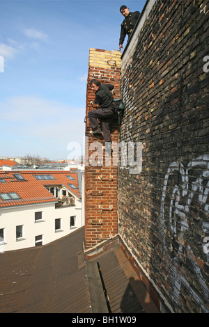 Fotografo arrampicata sui tetti di Berlino con lo spazzacamino, Berlino, Germania Foto Stock