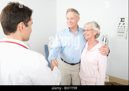 Metà adulto medico agitando la mano di uomo senior in coppia Foto Stock