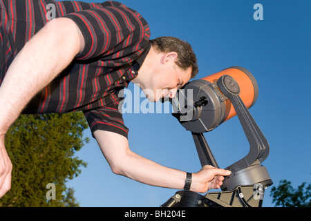 Un uomo che guarda attraverso un telescopio. Foto Stock