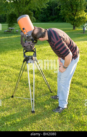 Un uomo che guarda attraverso un telescopio. Foto Stock