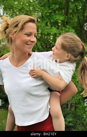 Giovane madre dando il suo bambino piggyback ride Foto Stock