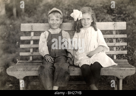 Infanzia innamorati tenendo le mani su una panchina nel parco Foto Stock