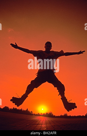 In-line skater jumping davanti al sole di setting Foto Stock