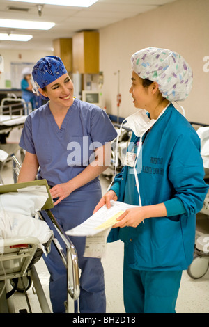 Vestito in 'scrubs", una donna chirurgo controlli con la sua infermiera circolante sulle autorizzazioni medico prima di un'operazione. Foto Stock