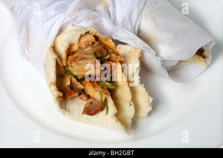 Due shawarma di pollo panino si avvolge su una piastra bianca. I rivestimenti sono un famoso fast-food take-away snack nel Medio Oriente. Foto Stock