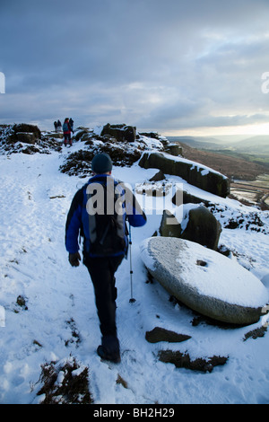 Gli escursionisti sul bordo Curbar nel Parco Nazionale di Peak District Derbyshire dopo la neve pesante Foto Stock