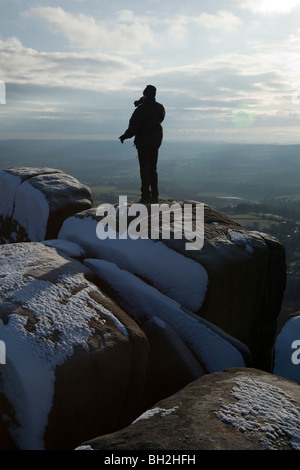 Persona sola in piedi sul bordo Curbar nel Parco Nazionale di Peak District Derbyshire dopo la neve pesante Foto Stock