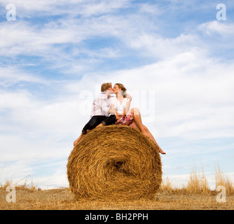 Donna e uomo baciare sulla balla di fieno Foto Stock