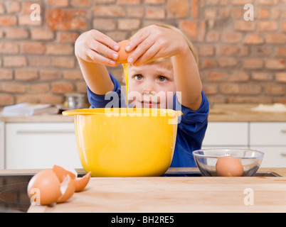 Ragazzo aggiungendo le uova di ciotola Foto Stock