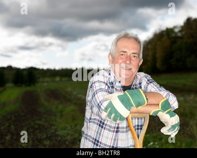 Uomo maturo in appoggio sulla pala Foto Stock