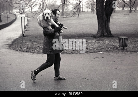 Mans miglior amico. Un uomo che cammina con il cane Hyde Park London, che porta un vecchio cane sulle spalle. 1979 1970S UK HOMER SYKES Foto Stock