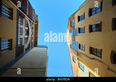 Vista verso l'alto del cielo blu e alti edifici con finestre di varie forme. Foto Stock