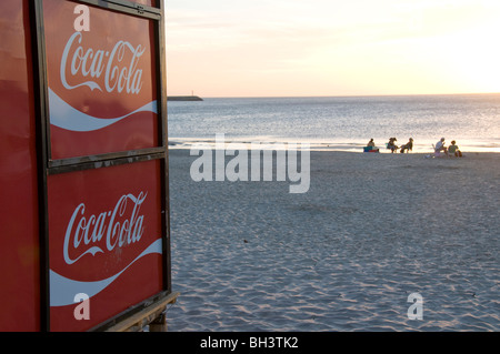 Uruguay. La gente a guardare il tramonto a Piriapolis beach, con Coca Cola segno Foto Stock