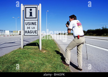 Fotografo di fronte al segno di entrata alla zona di fabbrica di La Hague (nucleare impianto di trattamento dei rifiuti), Manche (50), Francia Foto Stock