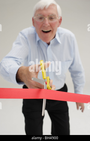 Imprenditore Senior circa per tagliare un nastro rosso, ridendo Foto Stock