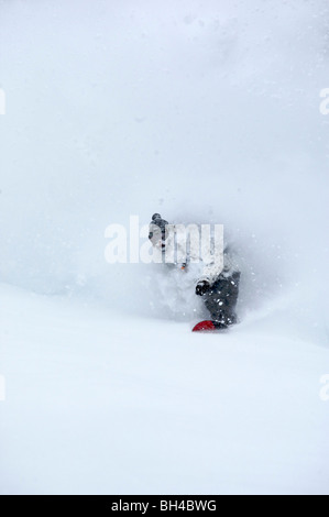 Un uomo snowboard attraverso la neve profonda. Foto Stock