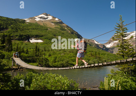 Una giovane ragazza escursioni su un ponte di sospensione nel Parco Nazionale di Glacier, Montana. Foto Stock