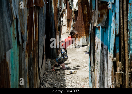 Una ragazza haitiana in esecuzione in un corridoio tra in baracche baraccopoli di cité soleil. Foto Stock