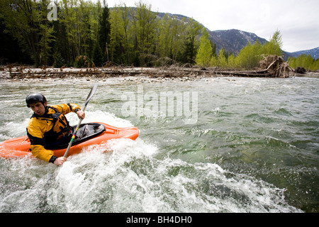 Un playboater gode di una piccola onda sulle rive di un fiume. Foto Stock