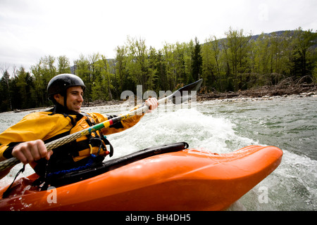 Un playboater gode di una piccola onda sulle rive di un fiume. Foto Stock